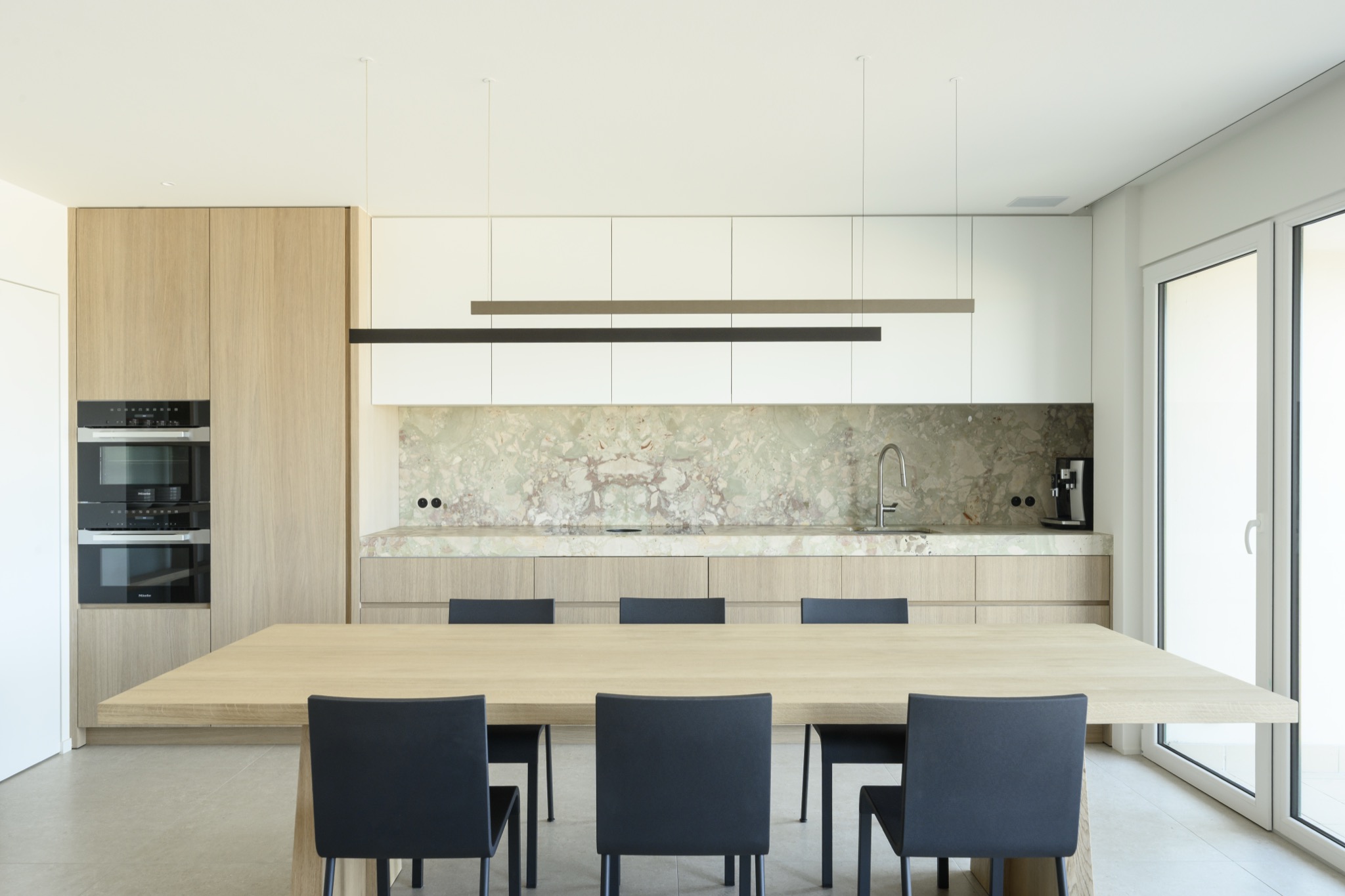 Keuken frontaal met eettafel en marmeren spatwand